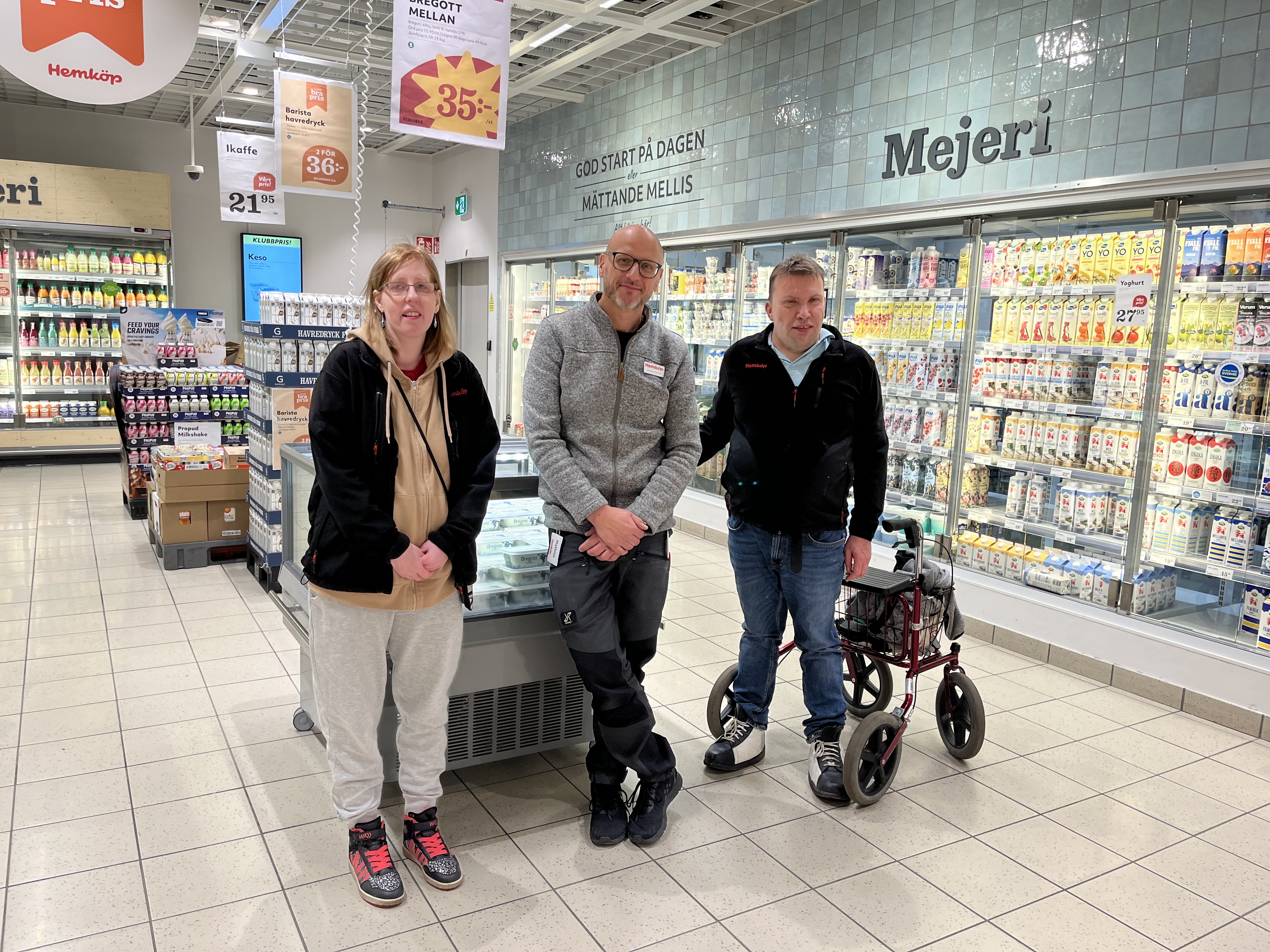 Tre glada medarbetare på Hemköp står vid kyldisken i en Hemköpbutik i Nacka Forum