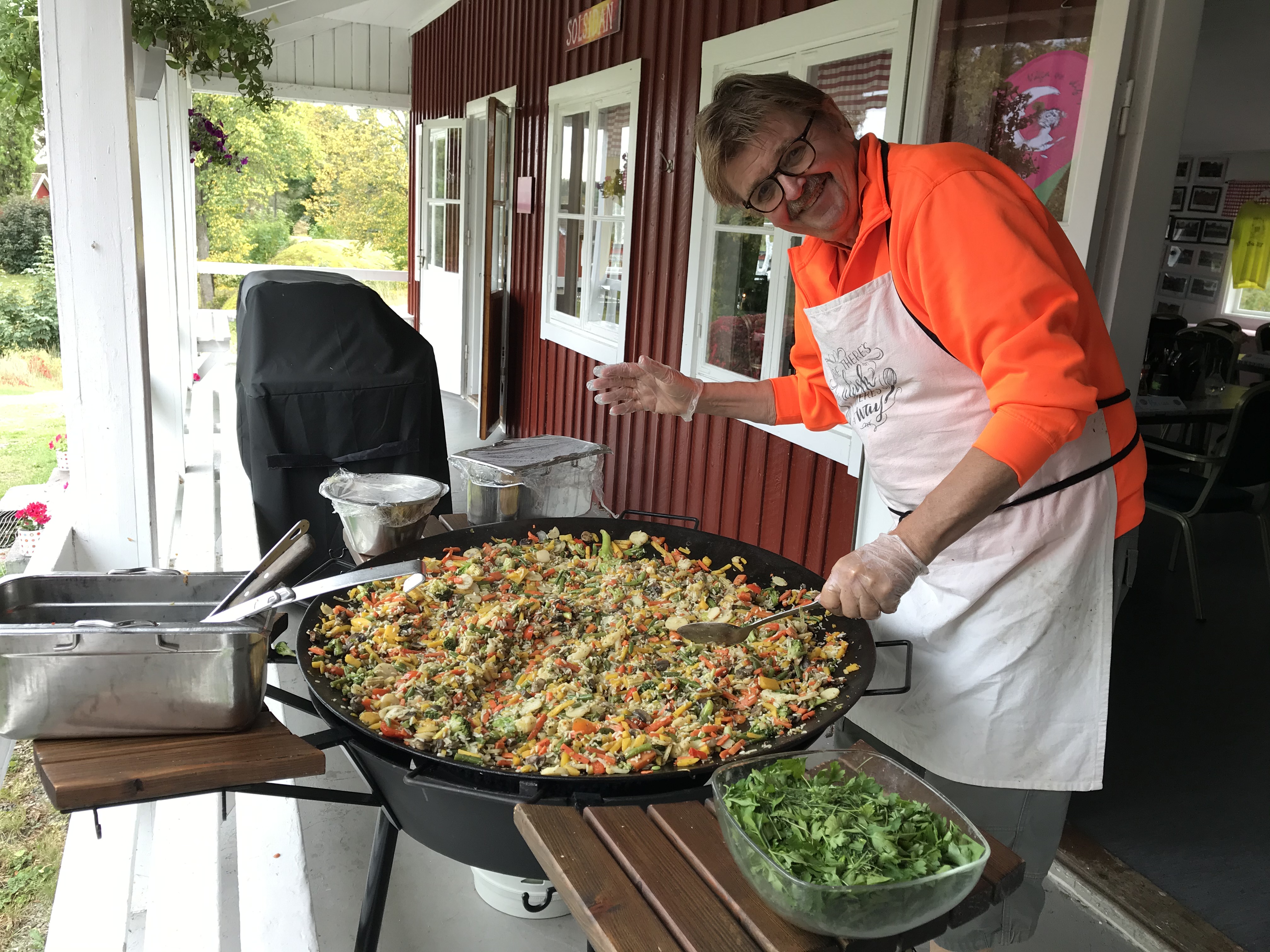 En glad man står och lagar mat utomhus
