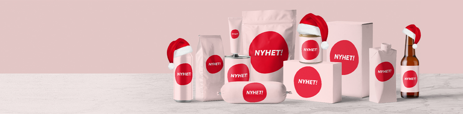 På ett bord står olika matförpackningar inslagna i rosa papper med ordet NYHET! på. Tre av produkterna har en liten tomtehatt på.