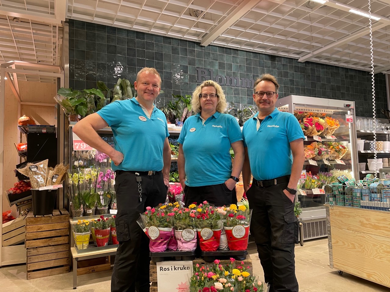 Tre glada manlig medarbetare står vid blommorna i en Hemköpbutik i Lindesberg